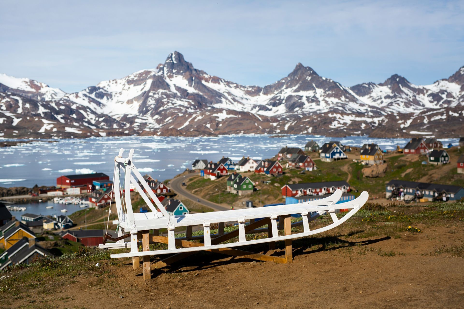 White sled overlooking the village of Tasiilaq with colorful houses and snow-capped mountains in Greenland.