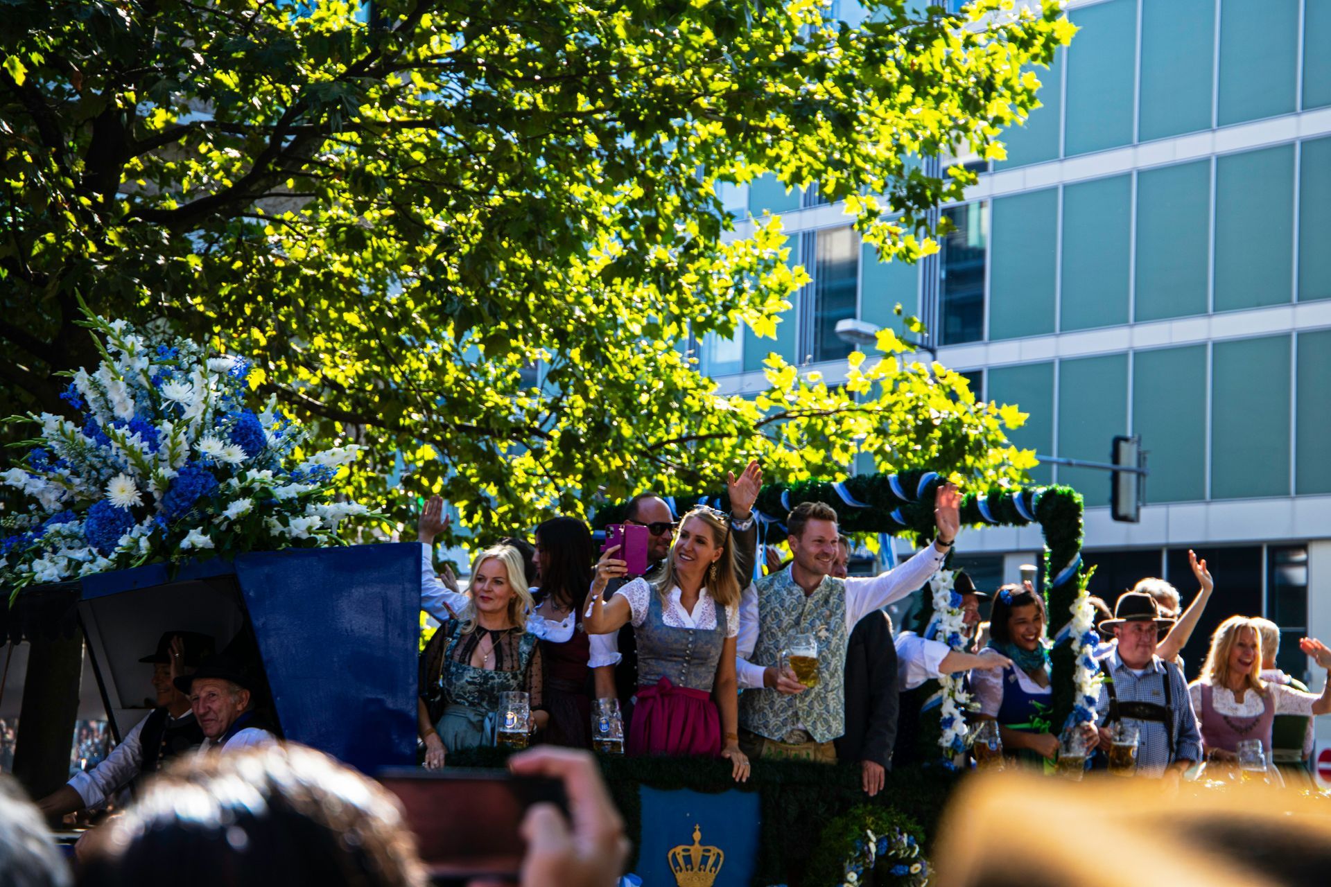 People in traditional Bavarian attire on a float, waving, at Oktoberfest in Munich, Germany.