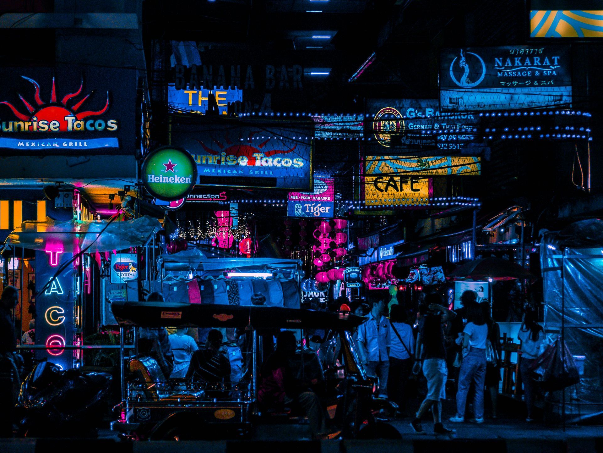A street lit up with neon lights at night in Bangkok, Thailand.