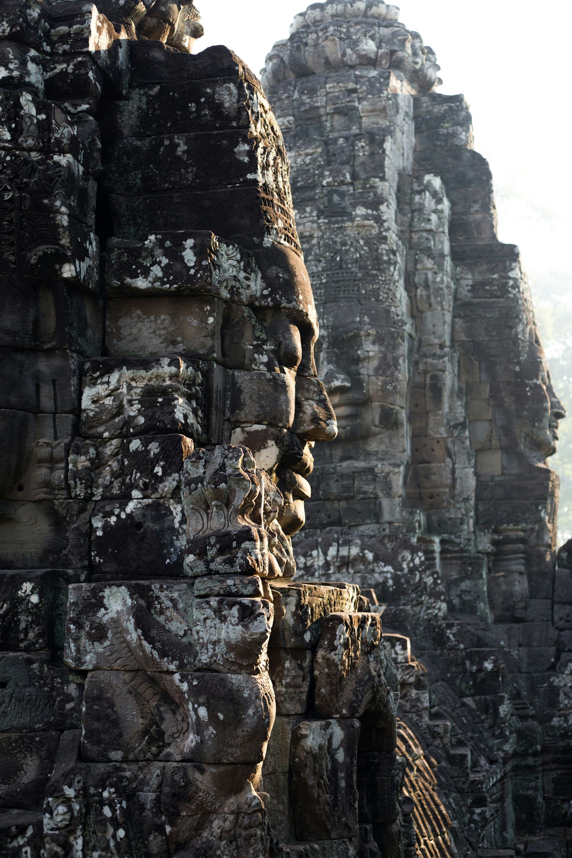 Stone faces of Bayon temple, Angkor, Cambodia, in silhouette against the morning light.