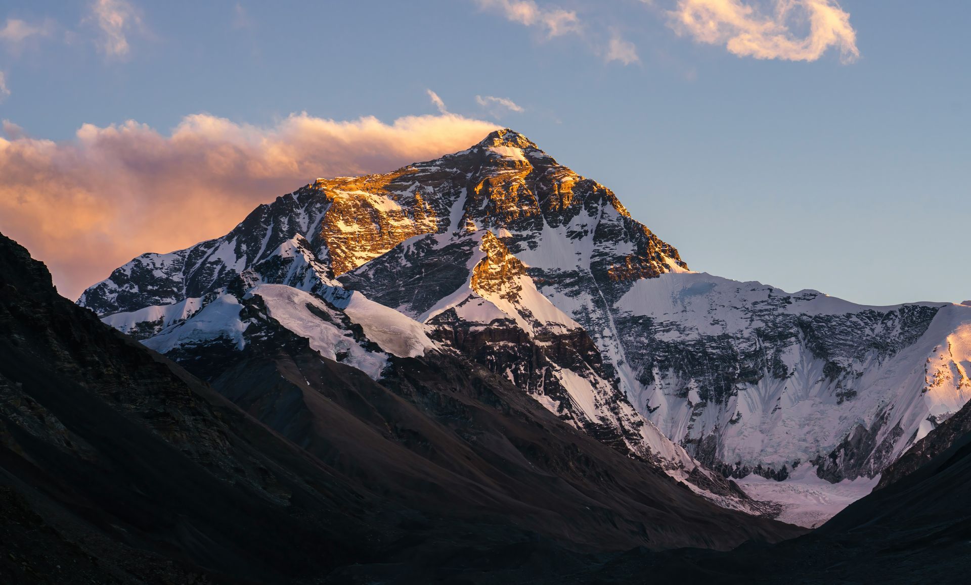 Snow-covered Mount Everest peak illuminated by the setting sun, with pink and gold clouds in Nepal.