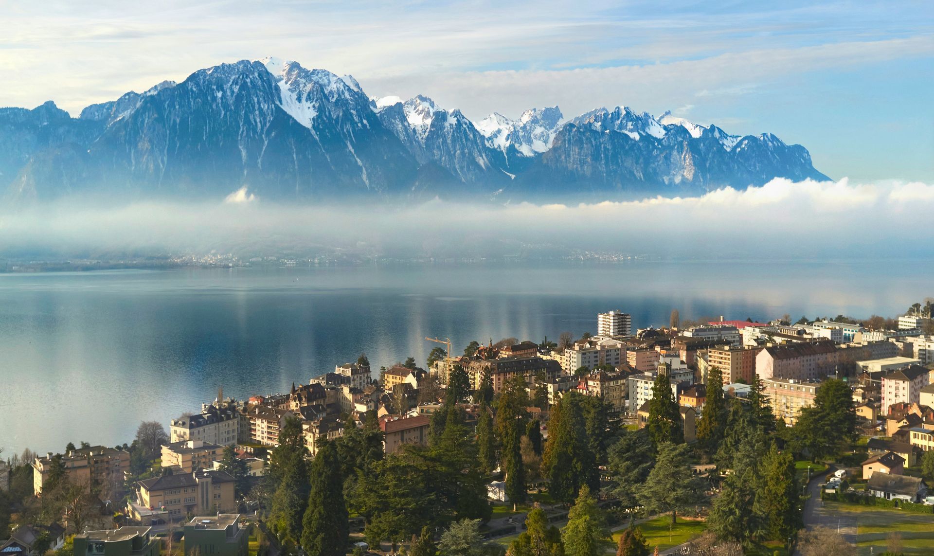 Town on a lake with snowy mountains in the background in Montreux, Switzerland.