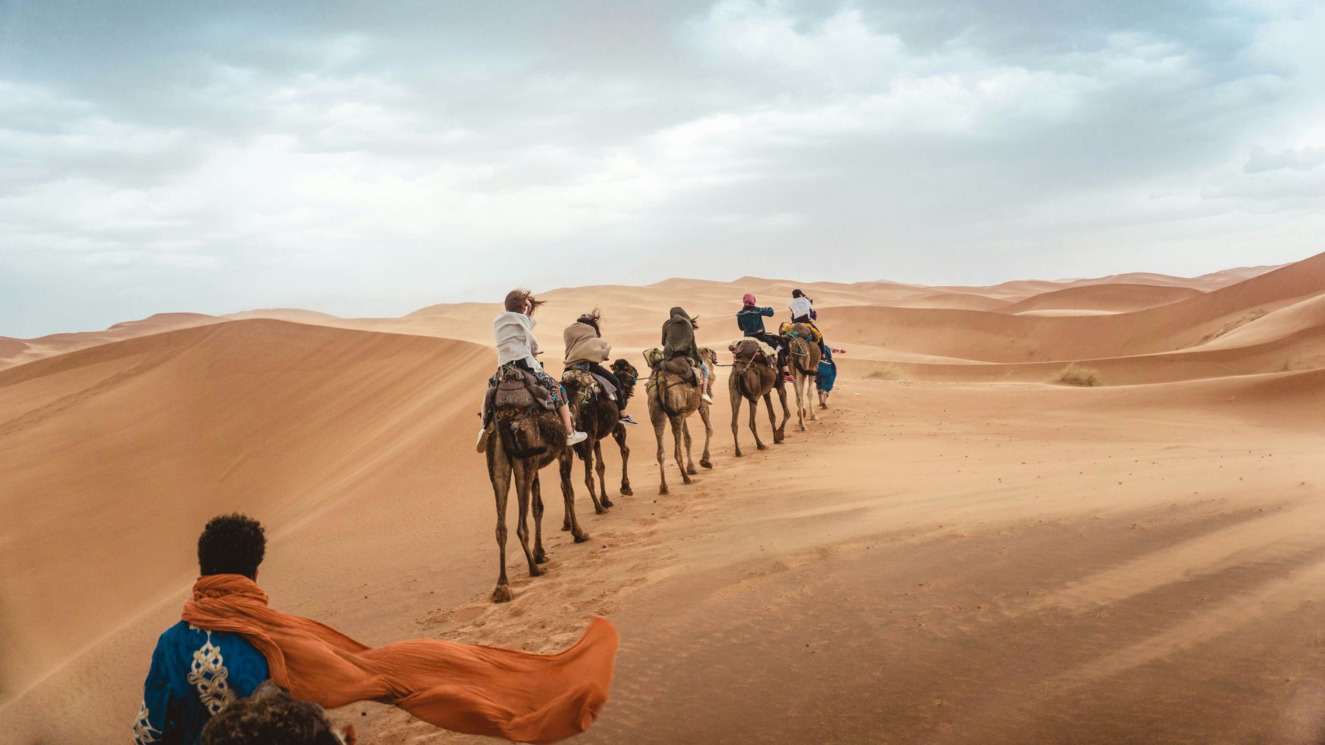 A group of people are riding camels in the desert.