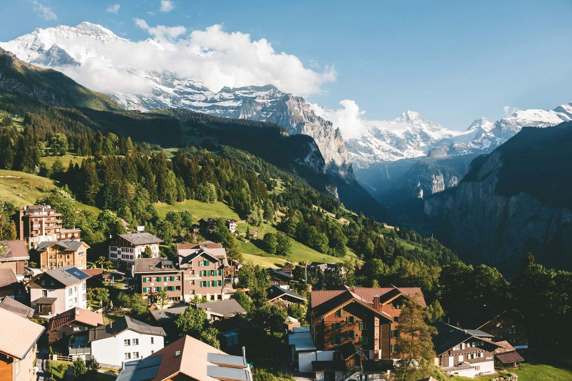 Village nestled in green hillside with snow-capped mountains in the background in Lauterbrunnen.