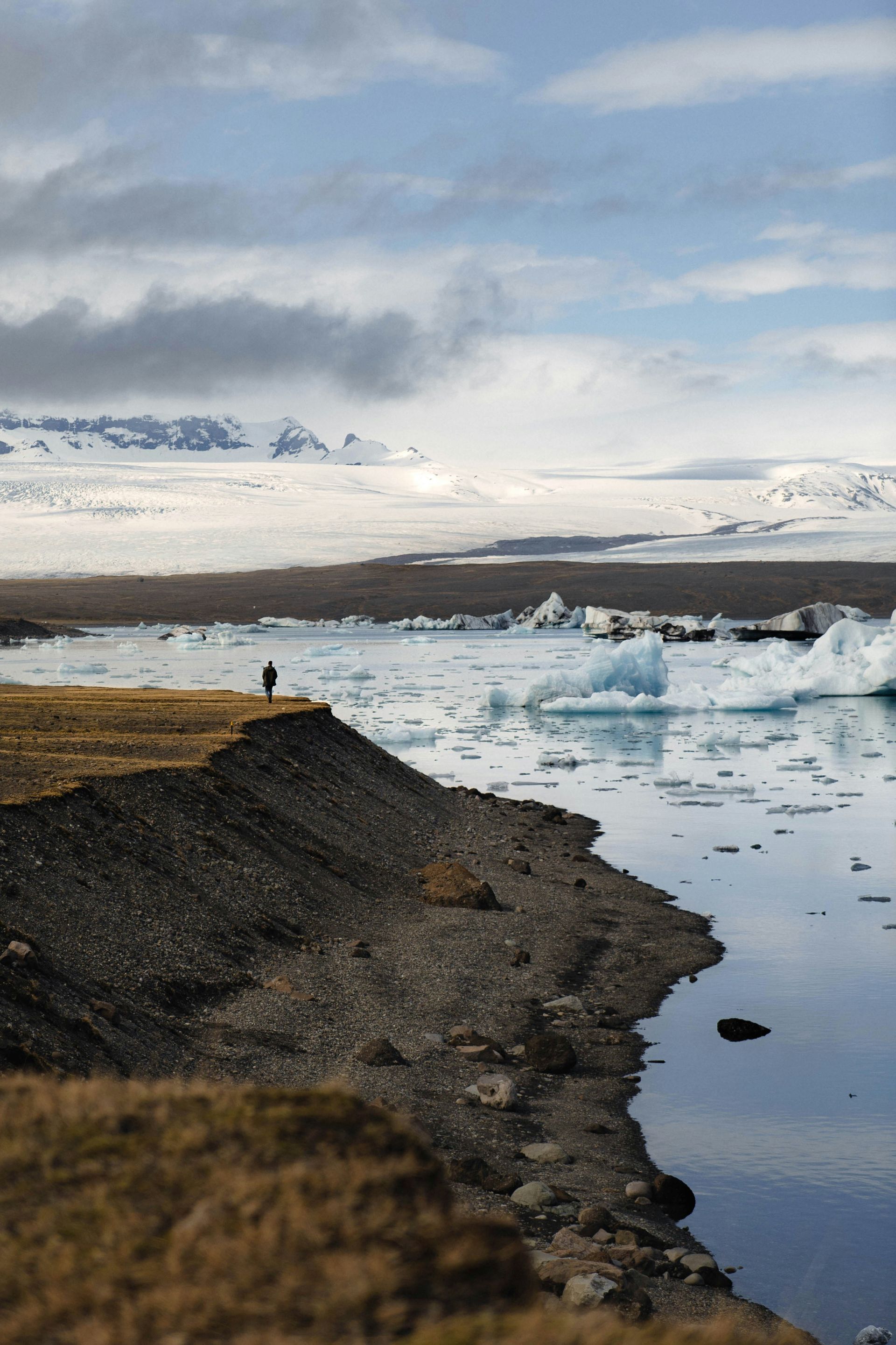 Person overlooking Jökulsárlón Glacier Lagoon with icebergs, mountains in Iceland.