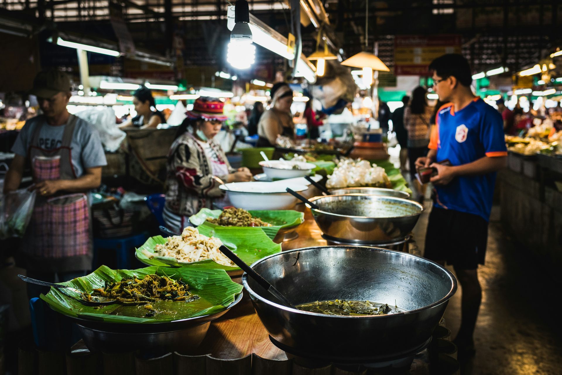 A man is standing in front of a table full of food at a night market in Chiang Mai, Thailand.