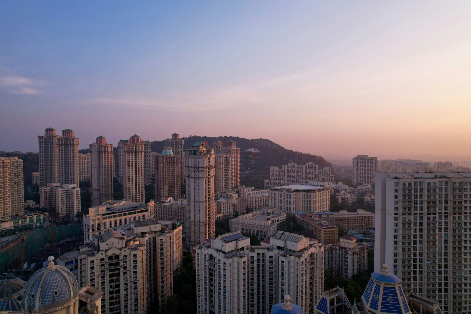 Mumbai skyline at dusk with tall buildings and a hill in the background in India.