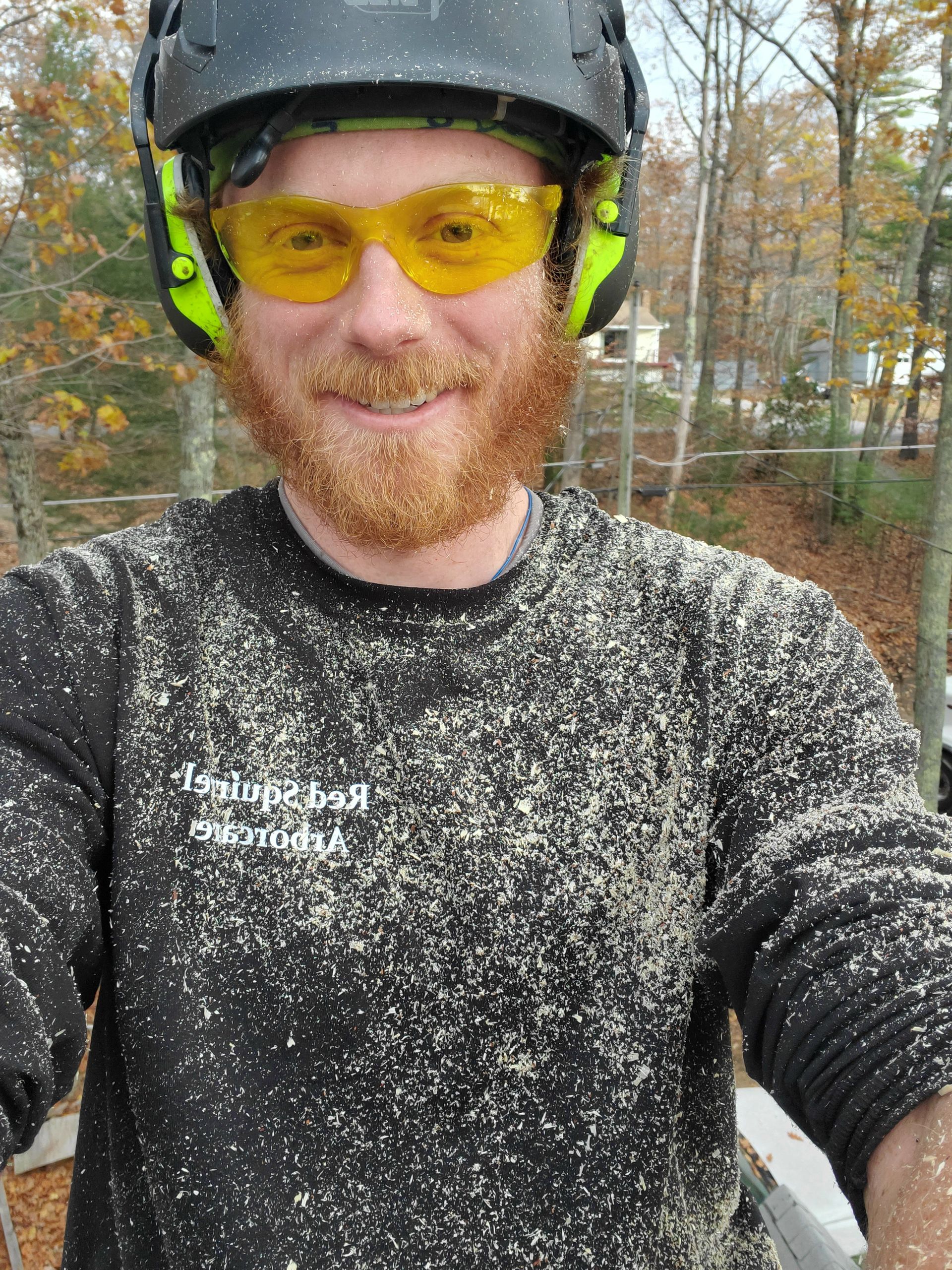 A man with a beard is wearing a helmet and safety glasses.