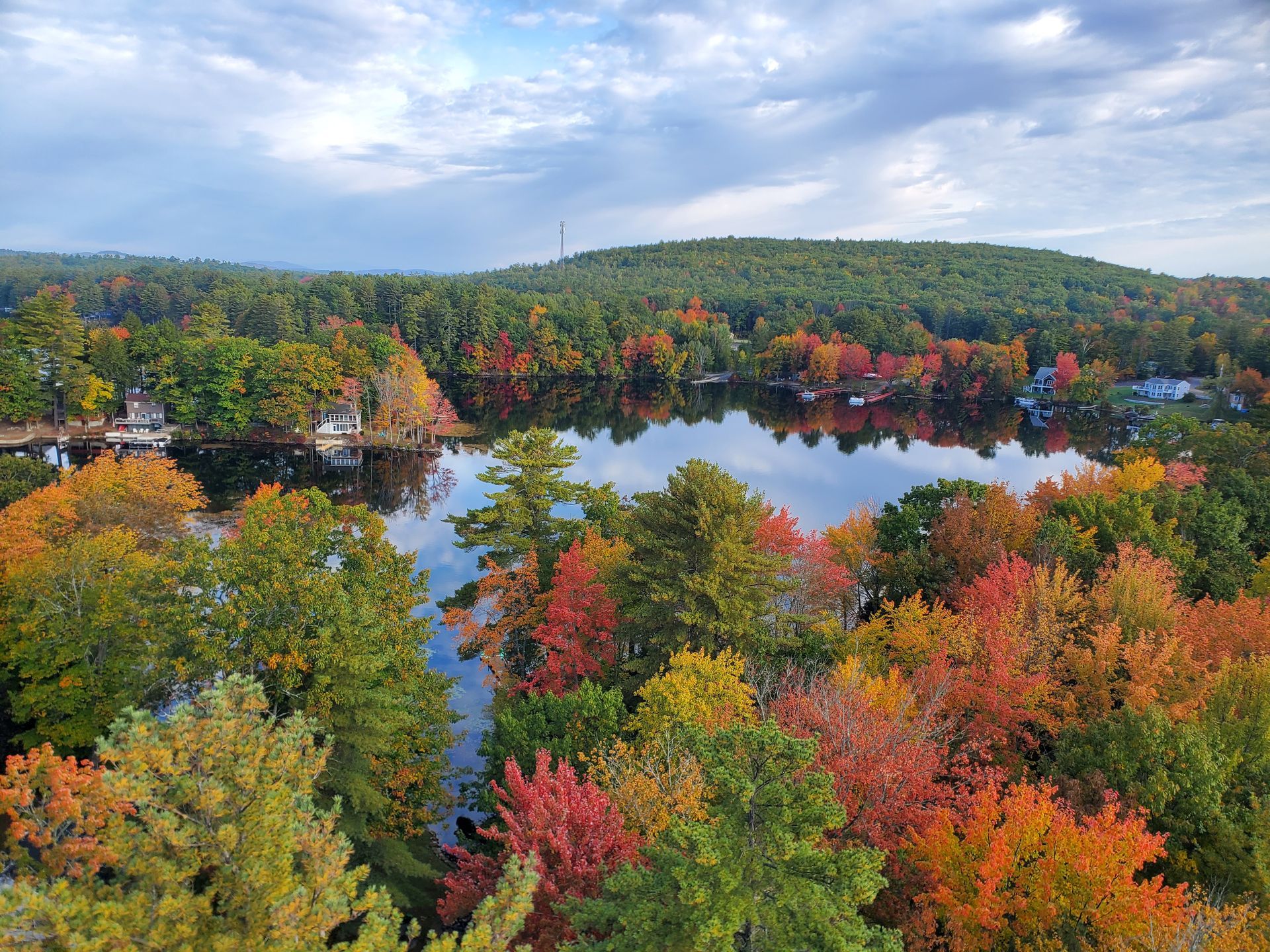 An aerial view of a lake surrounded by trees in autumn.