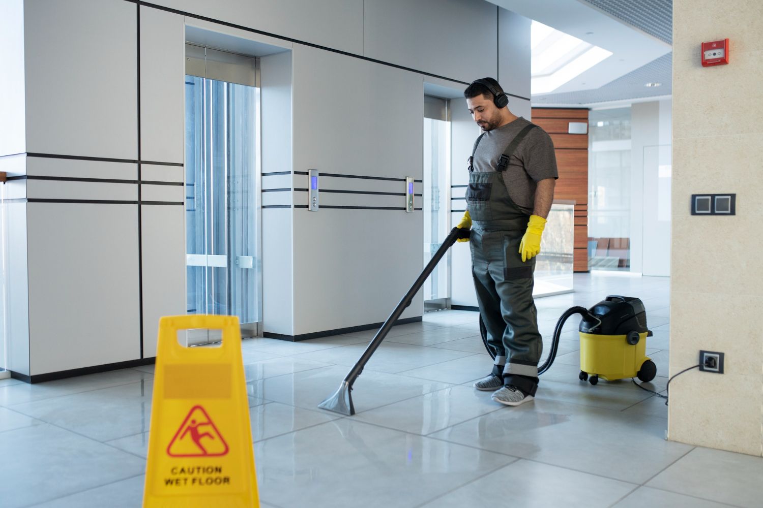 A man is cleaning the floor with a vacuum cleaner.