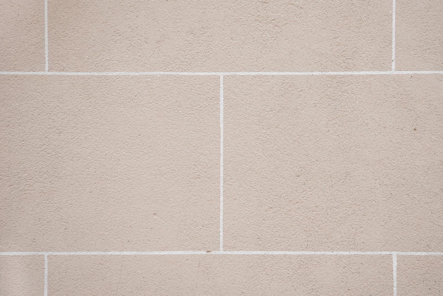 A close up of a white tile wall with white grout.