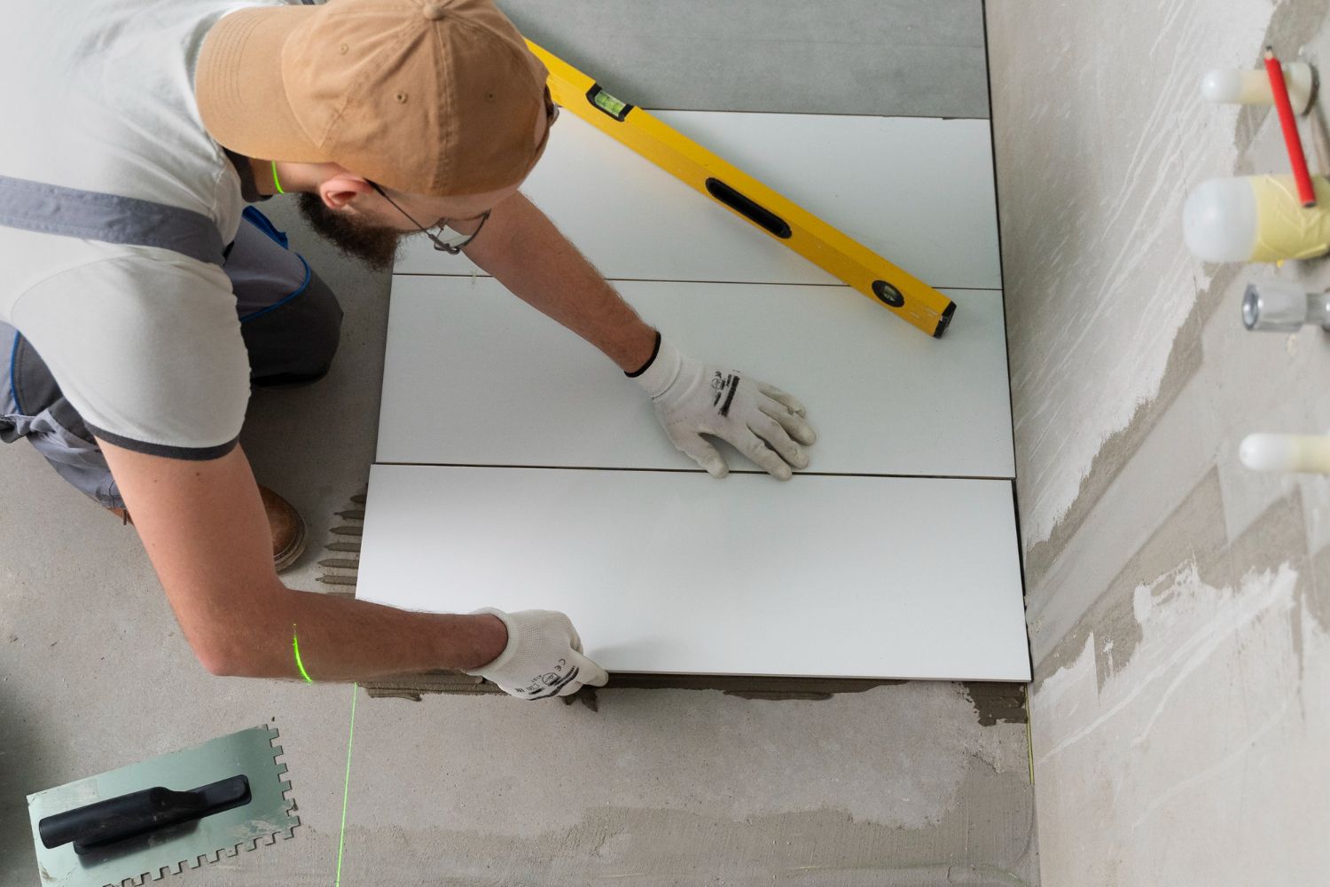 A man is laying tiles on the floor in a bathroom.