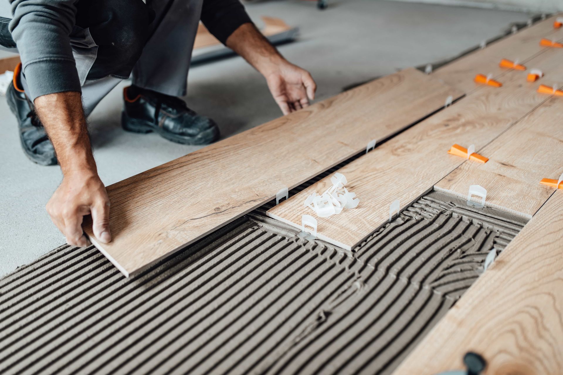 A man is laying wooden tiles on a floor.