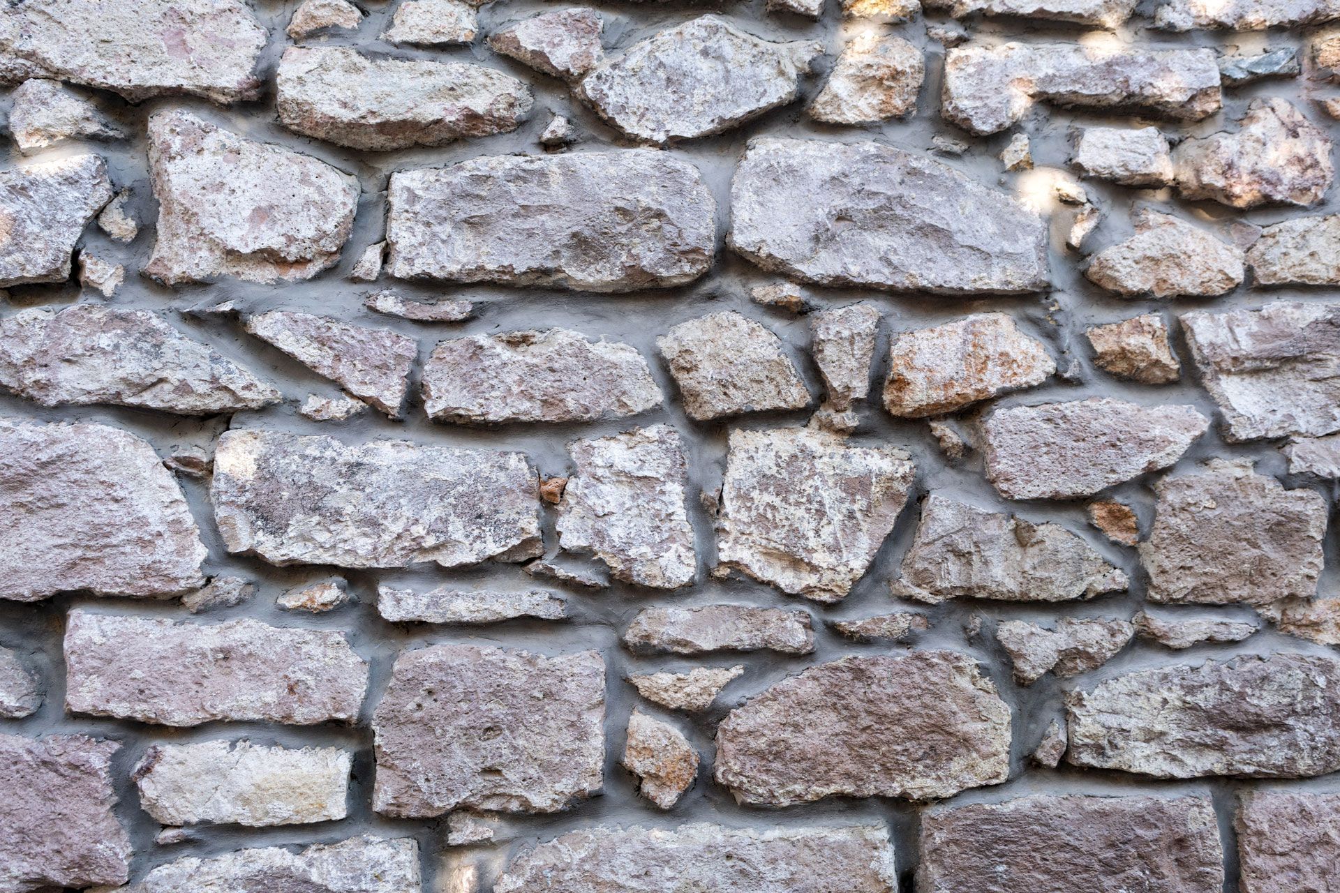 Rough stone wall, gray stones with cement mortar.