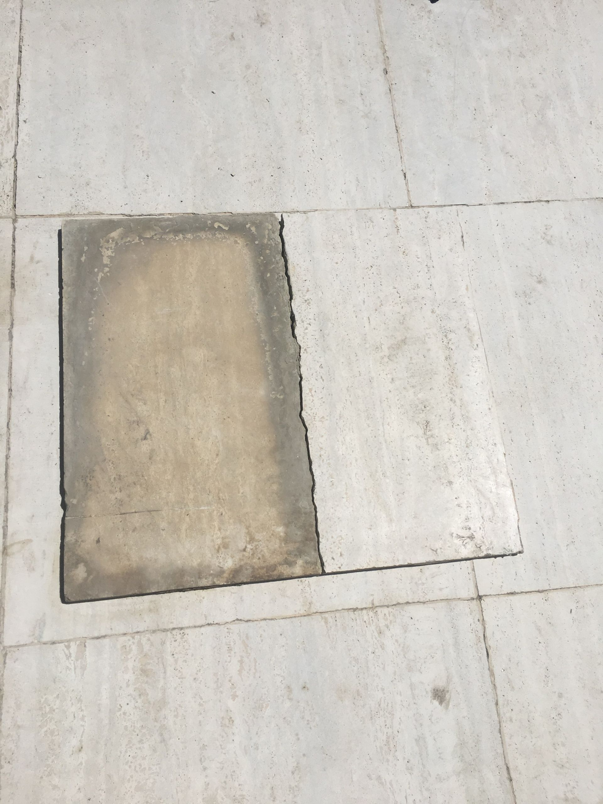 Gray concrete slab with darker stained square partially covering it.