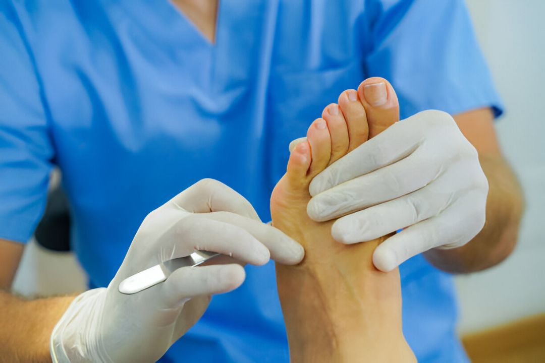 Podiatrist in gloves treating patient’s foot during clinical exam in professional medical setting.