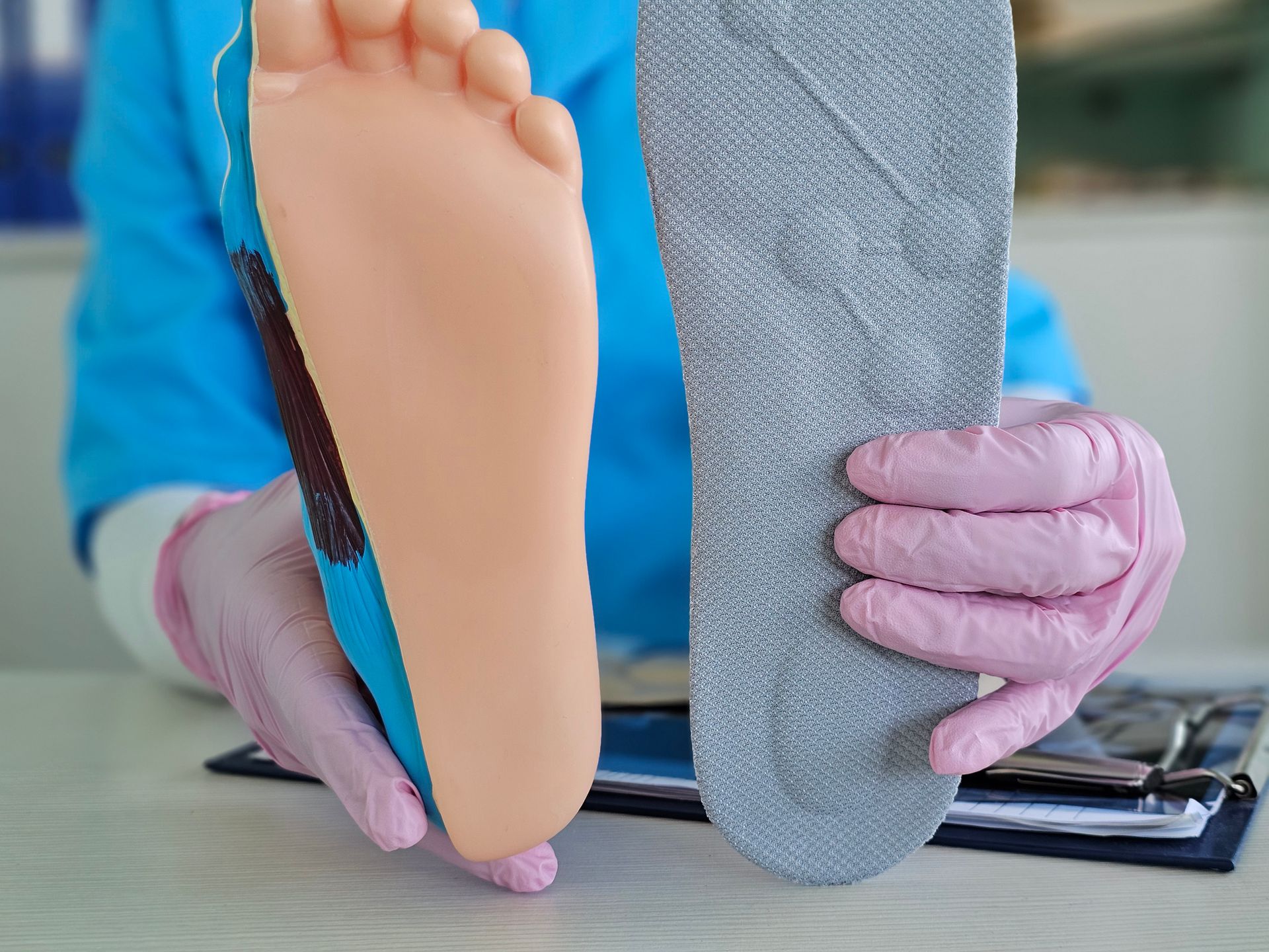 Podiatrist showing custom insole and foot model for podiatry orthotic supplies demonstration.