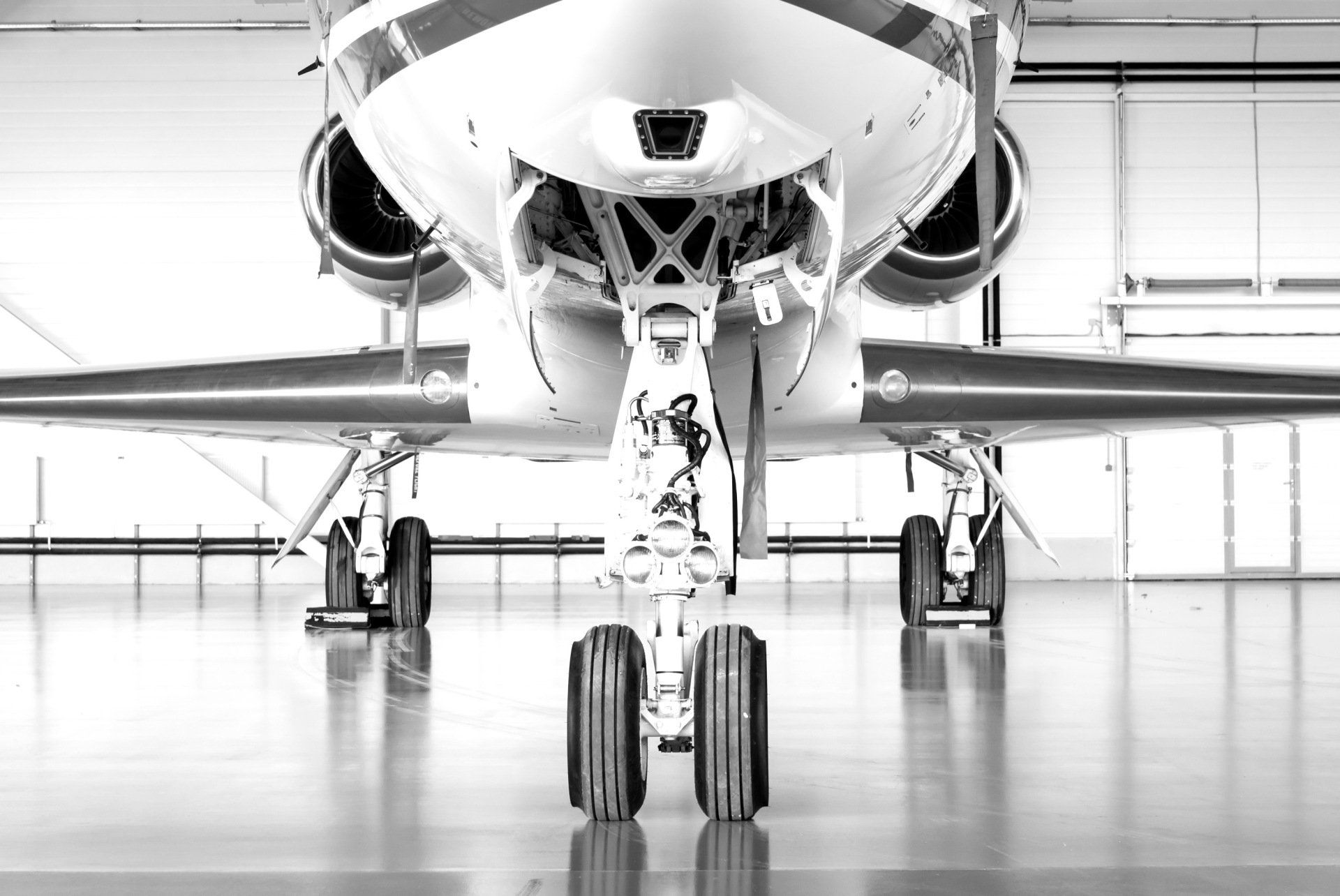 A black and white photo of a private jet parked in a hangar.