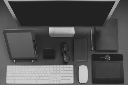 A black and white photo of a desk with a computer , keyboard , mouse and tablet.