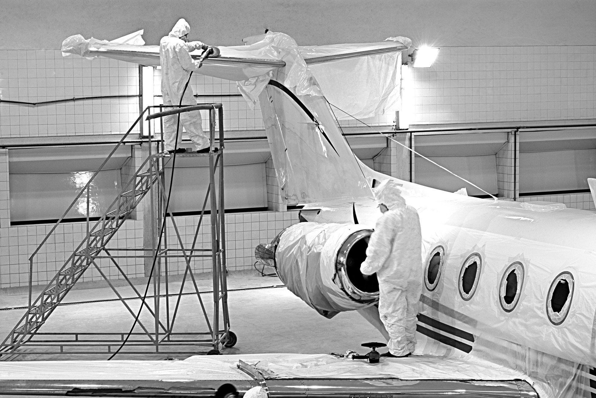 A black and white photo of a plane being painted
