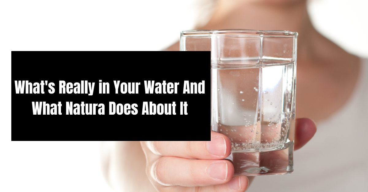 Hand holding a glass of water with text: “What’s Really in Your Water and What Natura Does About It”