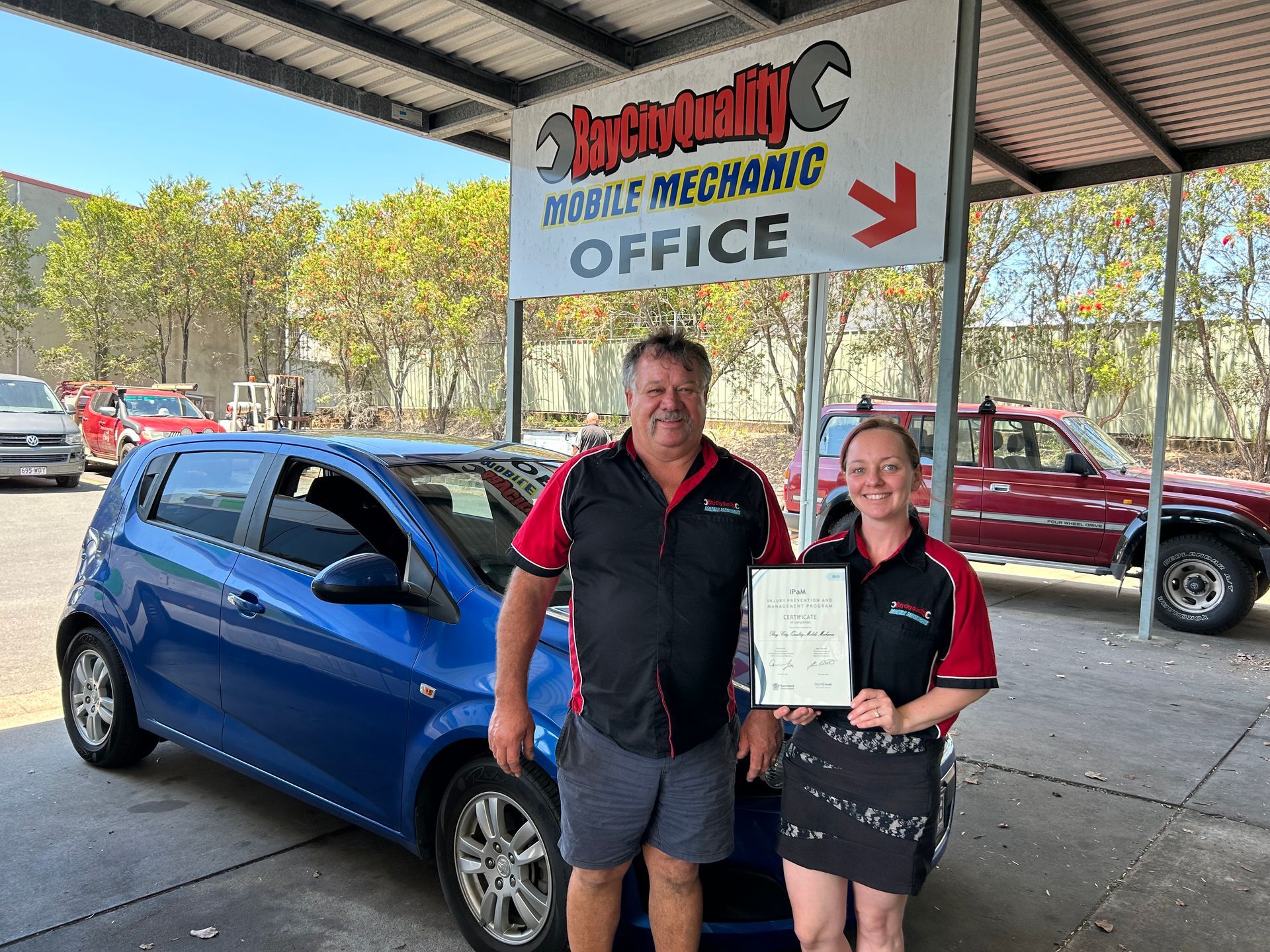 A Man Is Cleaning A Car With A Yellow Cloth — Bay City Quality Mobile Mechanic In Pialba, QLD