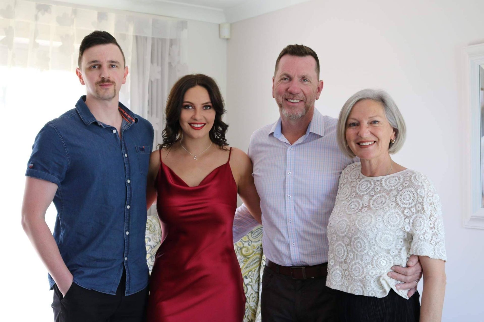 Four people stand close together in a brightly lit indoor setting, smiling for a portrait.