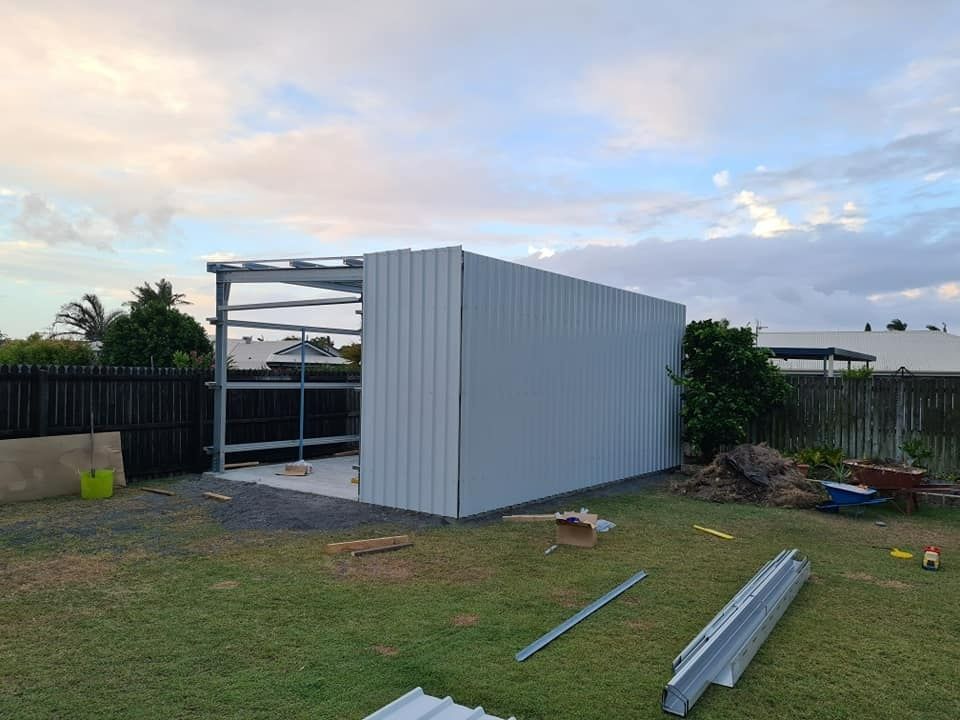A White Shed Is Being Built In A Backyard — Bushman Sheds in Bundaberg East, QLD