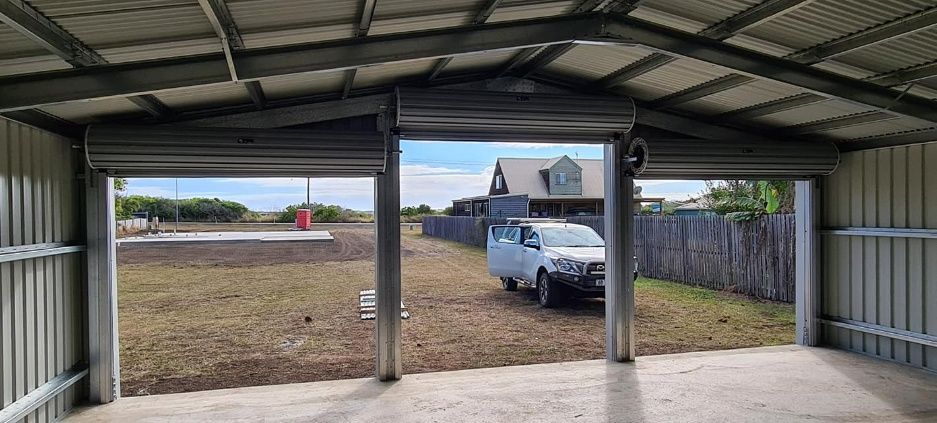 A White Truck Is Parked In A Garage With The Doors Open — Bushman Sheds in Bundaberg East, QLD