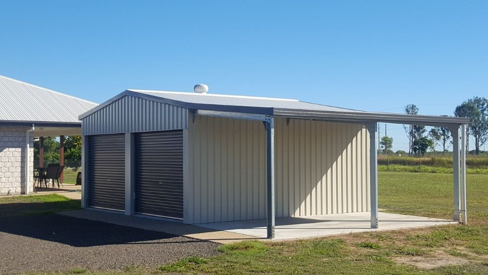 A Garage With A Canopy Over It Is In The Middle Of A Grassy Field — Bushman Sheds in Bundaberg East, QLD