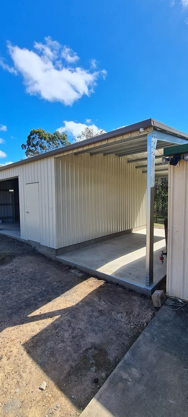 A White Shed With A Metal Roof Is Sitting On Top Of A Dirt Field — Bushman Sheds in Woodgate, QLD
