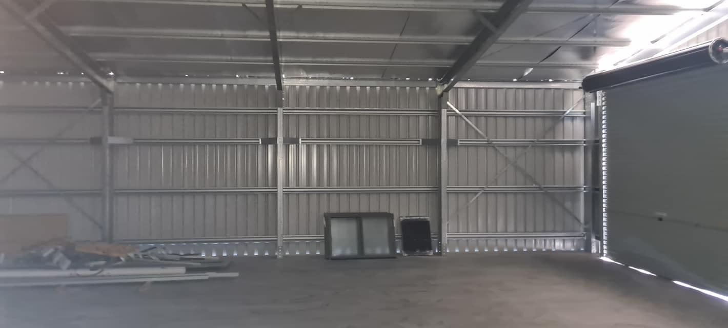 A Large Empty Warehouse With A Sliding Door And A Window — Bushman Sheds in Bundaberg East, QLD