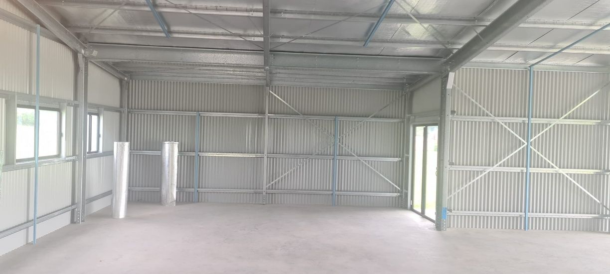 A Large Empty Warehouse With A Metal Roof And Walls — Bushman Sheds in Bundaberg East, QLD