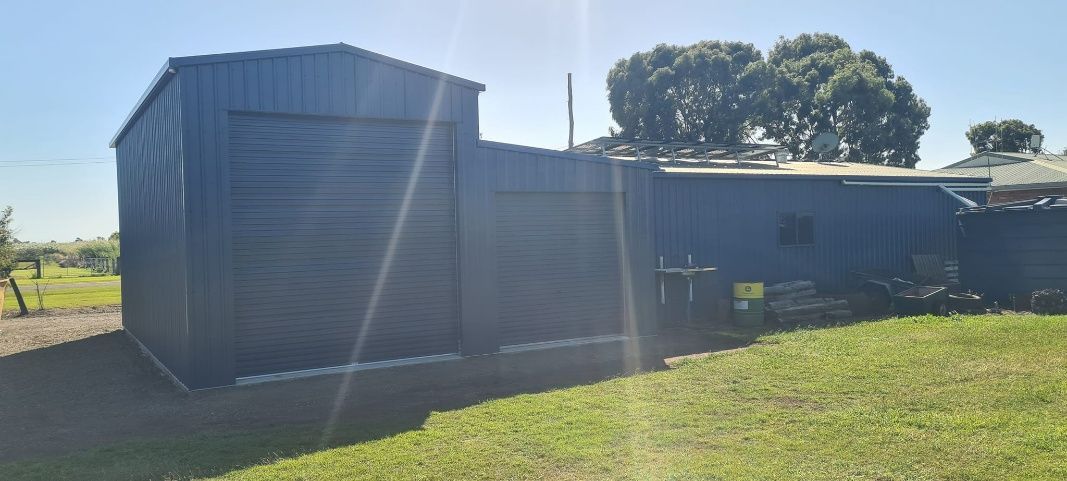 A Shed Is Sitting In The Middle Of A Grassy Field — Bushman Sheds in Bundaberg East, QLD