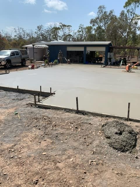 A Concrete Floor Is Being Poured In Front Of A Garage — Bushman Sheds in Childers, QLD