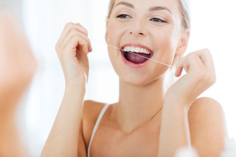Young Woman Flossing Teeth — Dentistry Services in Cairns, QLD