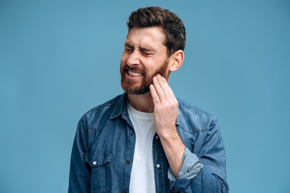 Man Pressing Sore Cheek — Dentistry Services in Cairns, QLD