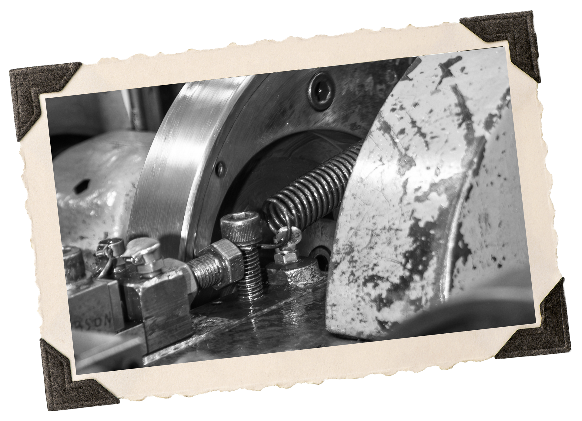 Close-up of a metal machine with a coiled spring, bolts, and gears, in black and white.