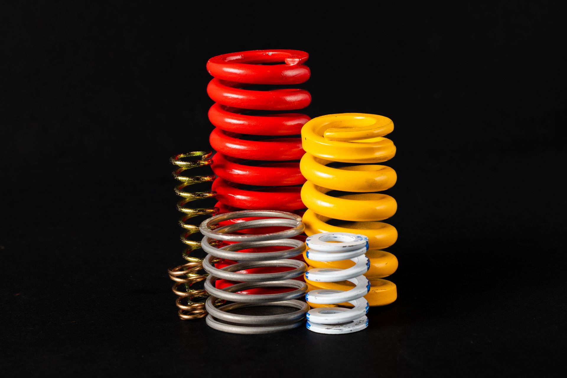 Several brightly colored coil springs arranged on a black background.