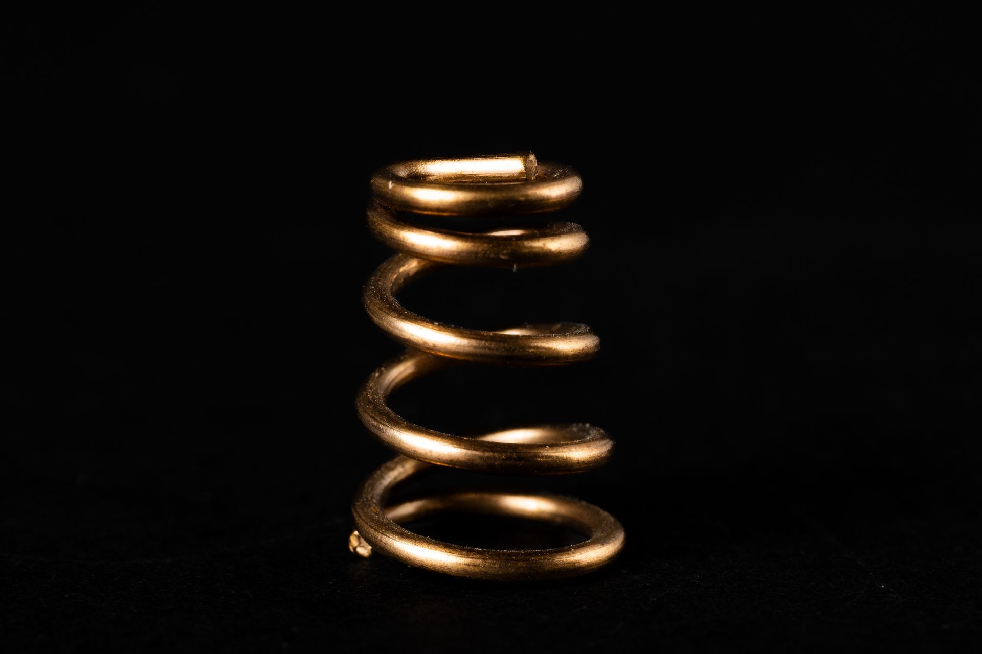 Golden coil spring against a black background.
