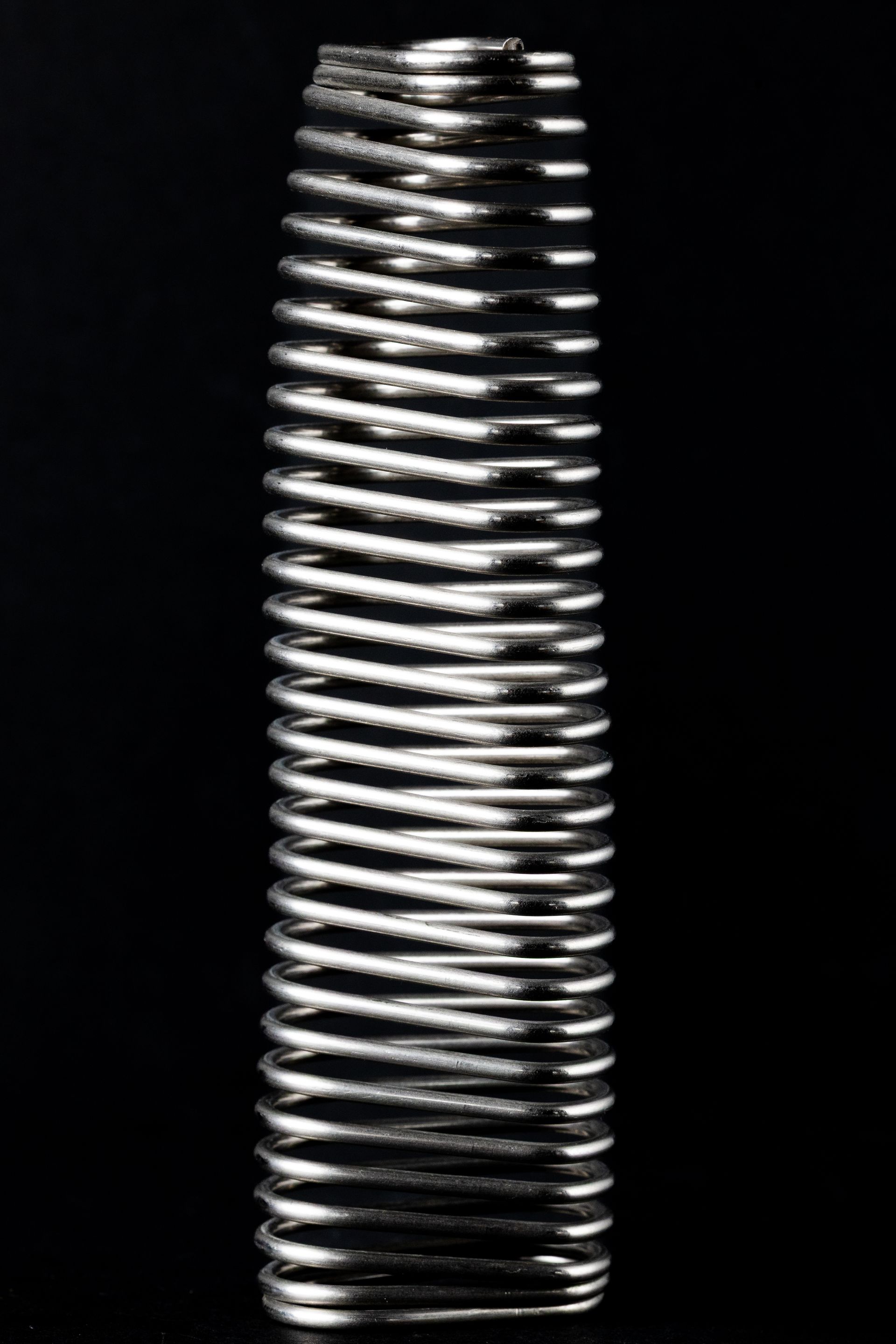 Silver metal spring against a black background.