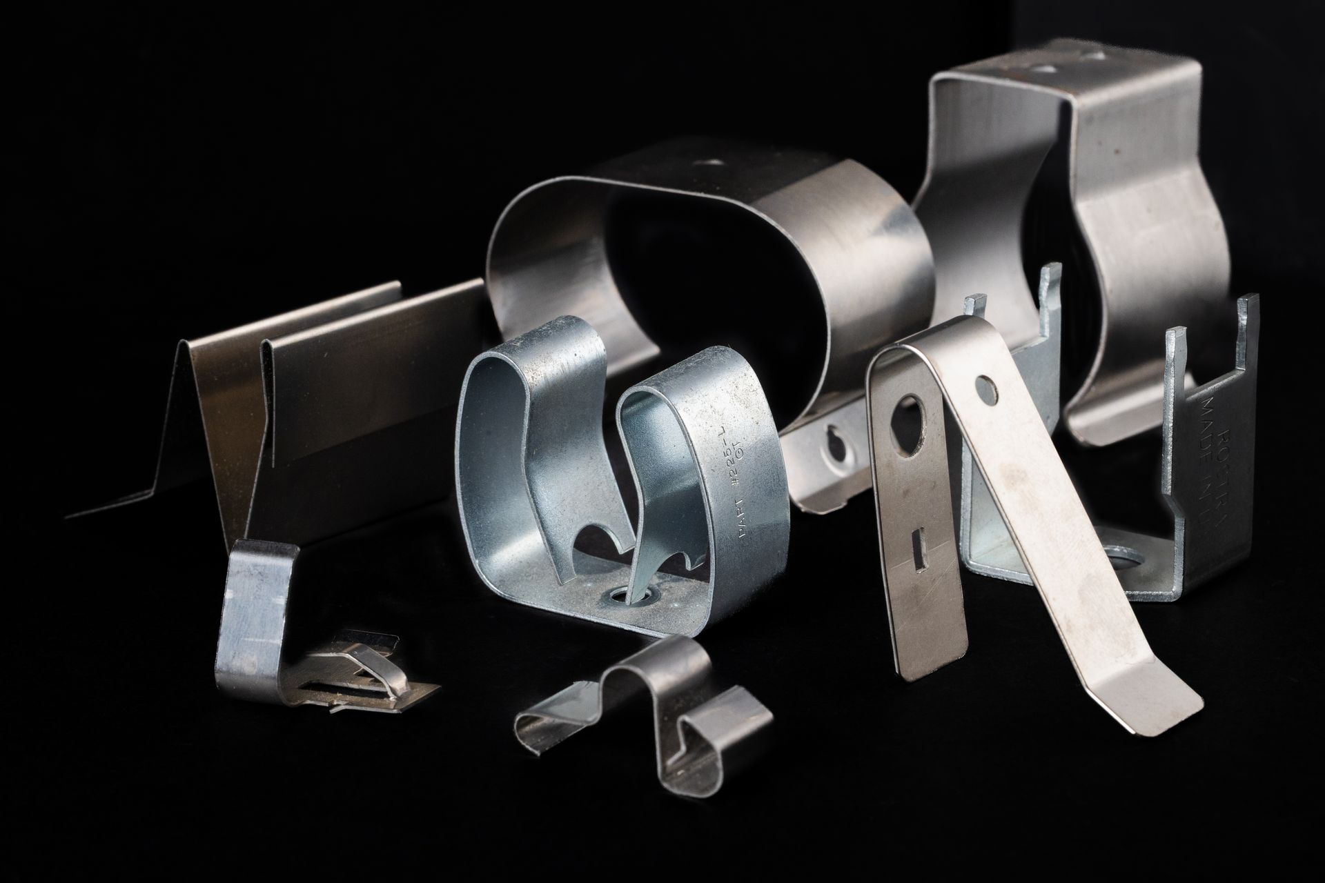 Various metal spring clips displayed against a dark background.
