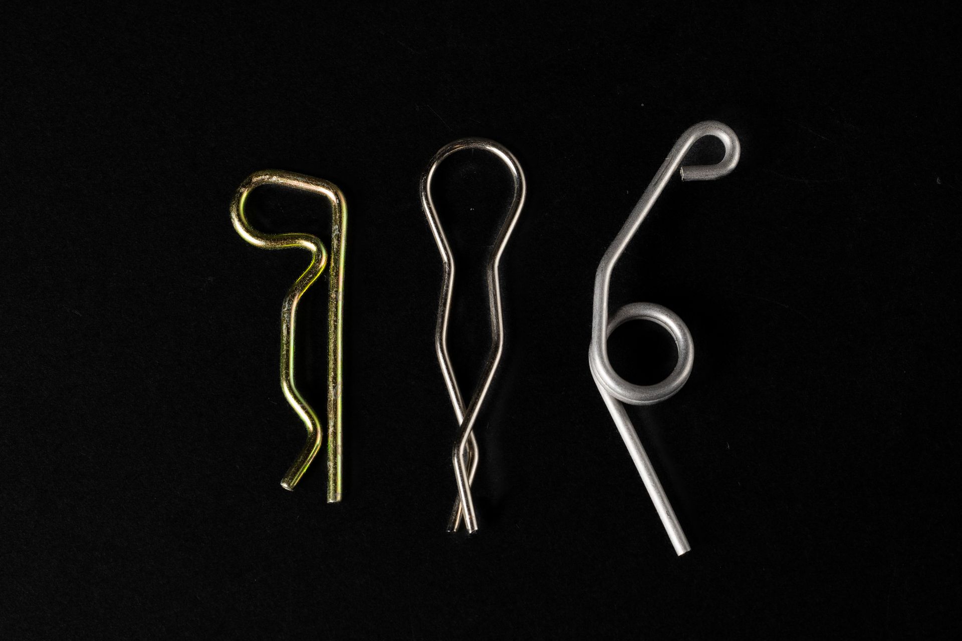 Three metal cotter pins on a black background.