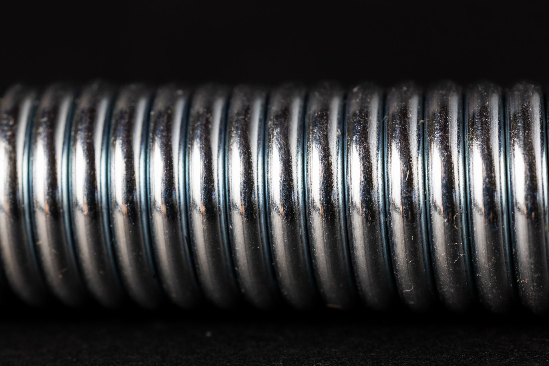 Close-up of a silver coiled spring against a black background.