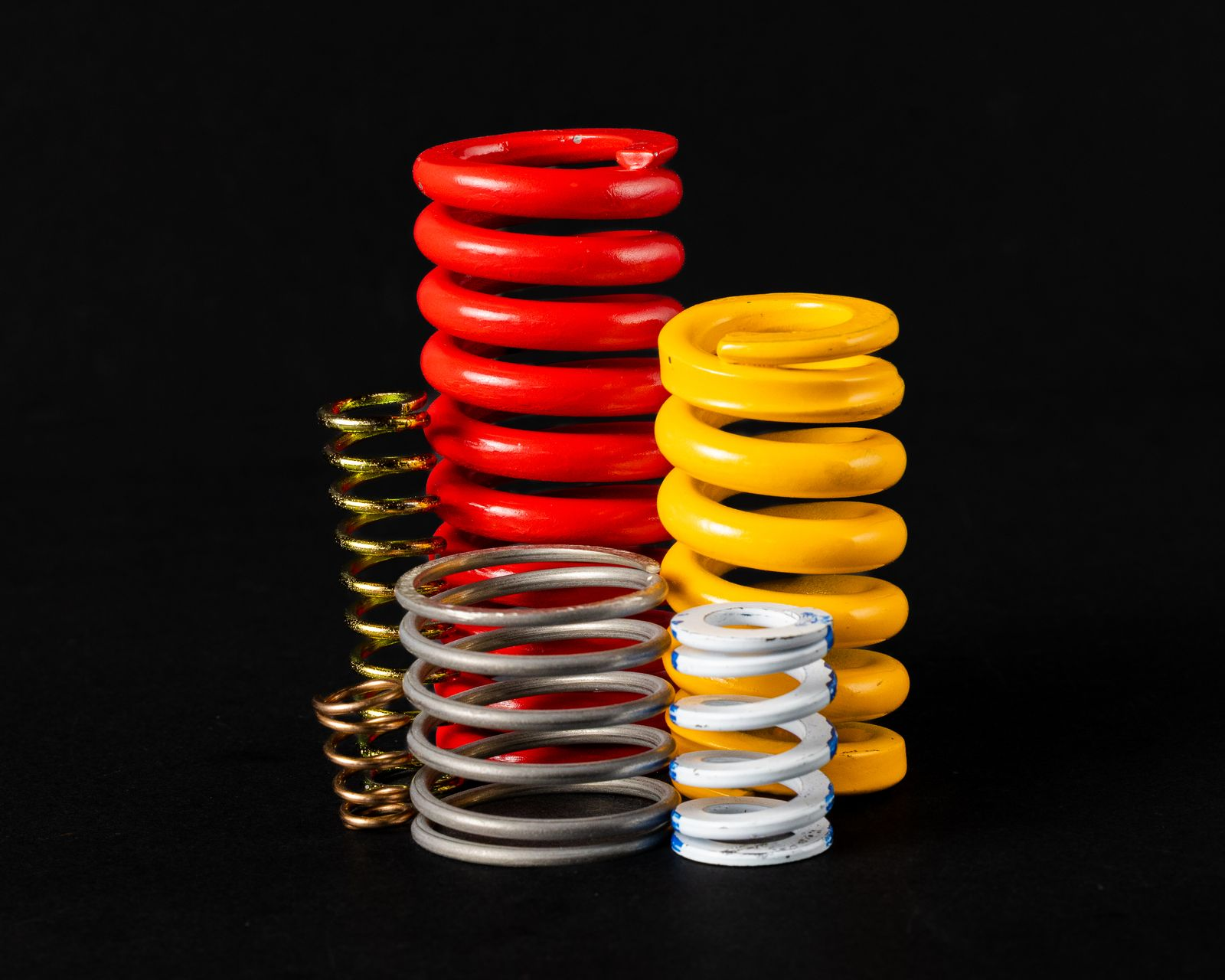 Group of colorful coil springs against a black background.