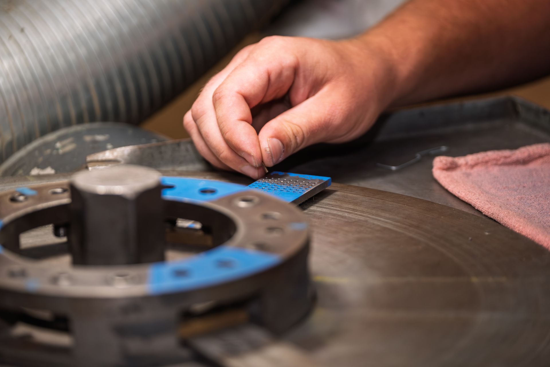 A person polishes a small stone on a spinning machine. Close-up on the hand and the grinding process.
