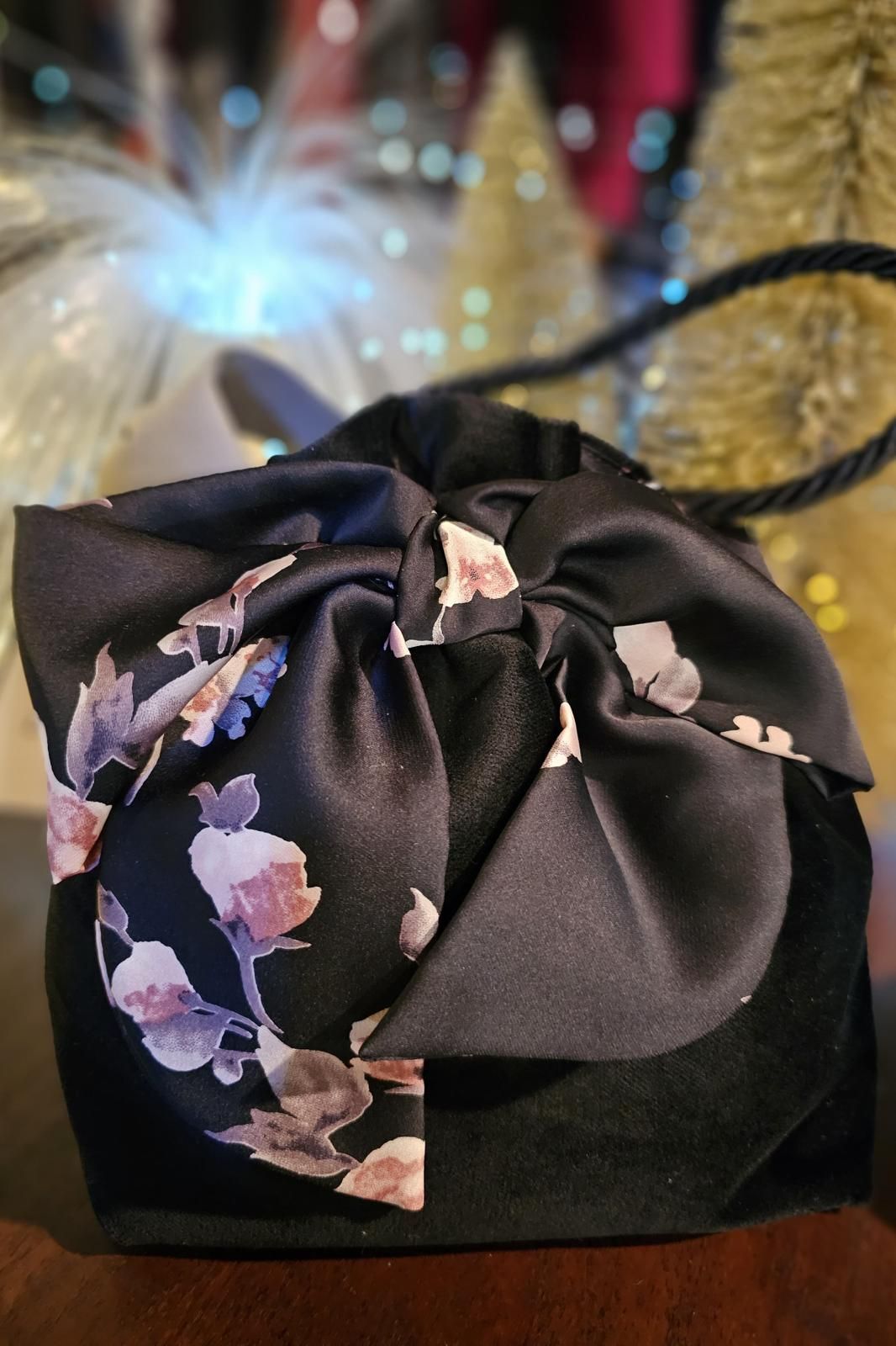 Una borsa nera con dei fiori sopra è appoggiata su un divano