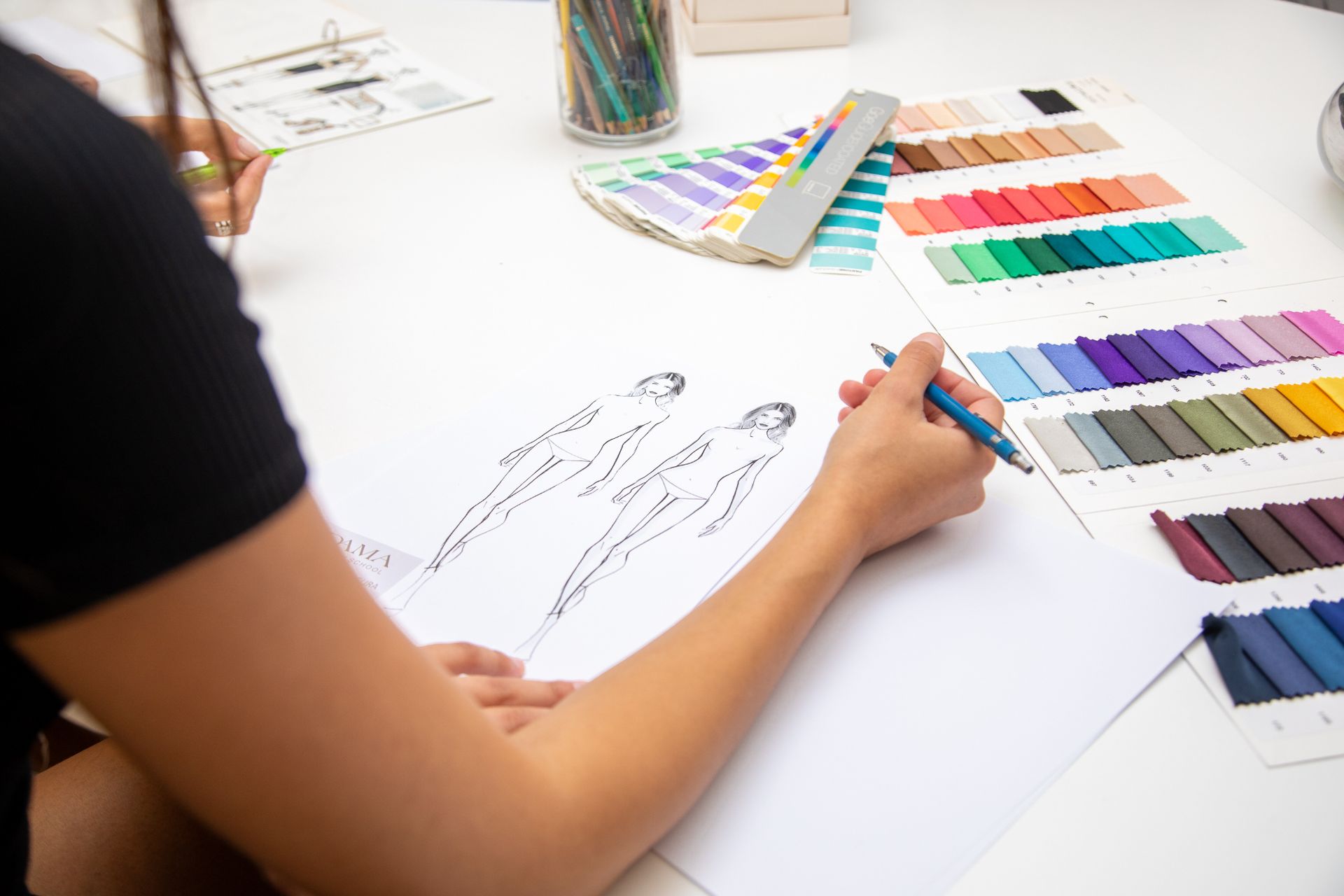 Una donna è seduta a un tavolo e disegna su un pezzo di carta.