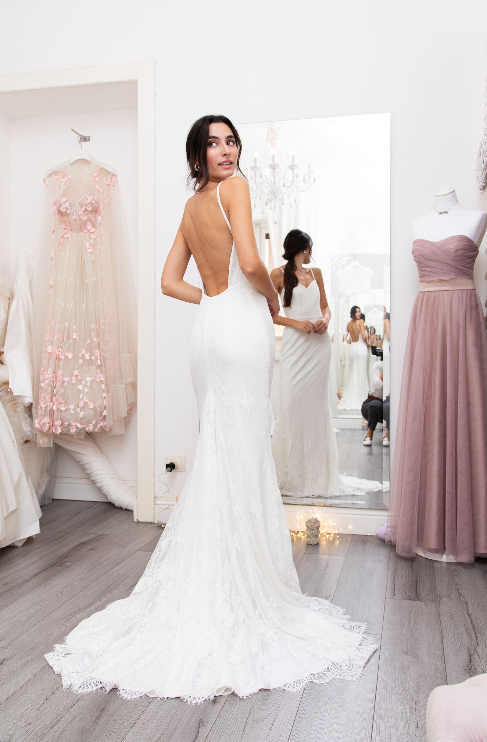 Una donna in abito da sposa è in piedi davanti allo specchio.