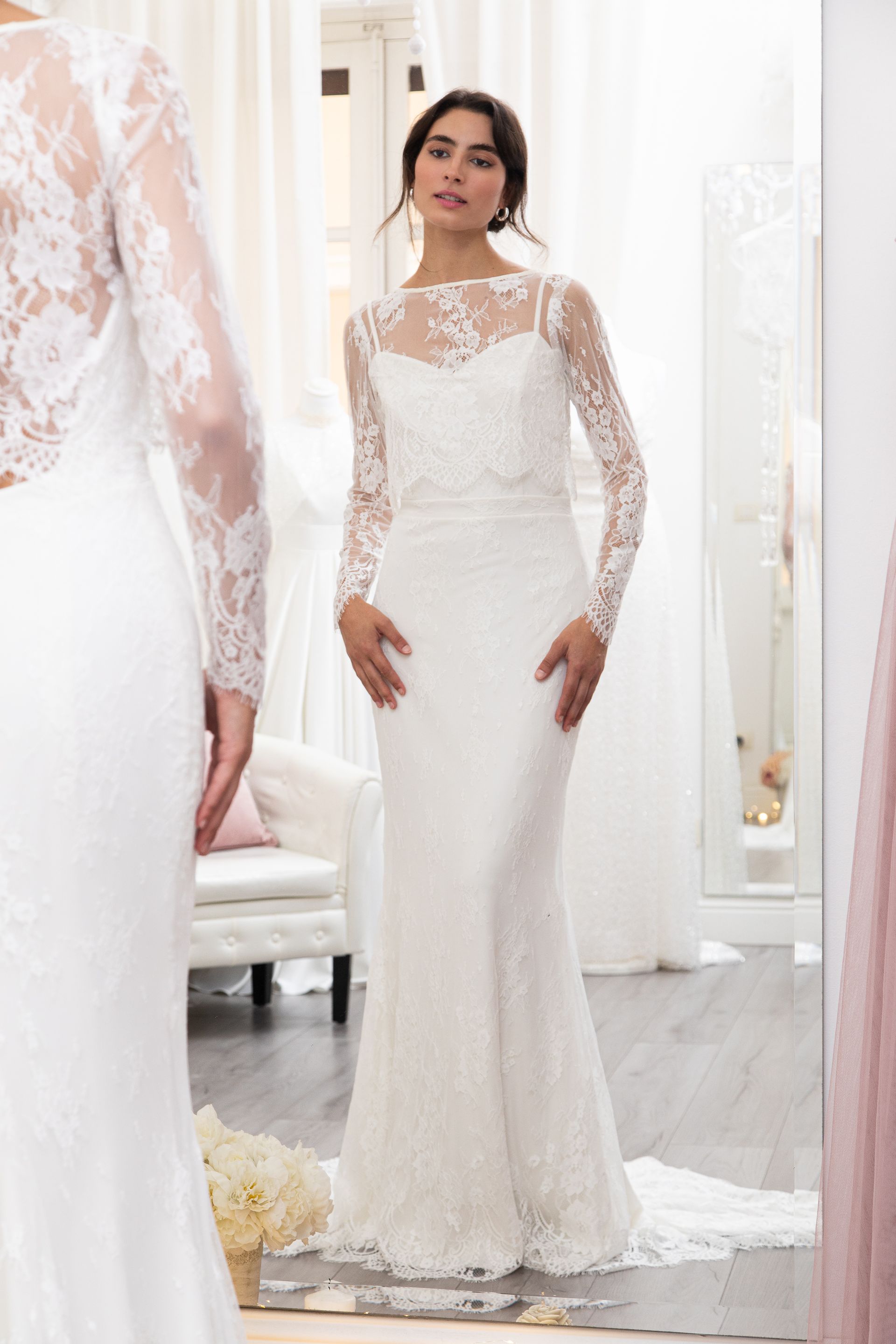 Una donna in abito da sposa è in piedi davanti allo specchio.